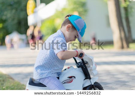 Little cute child riding scooter in city street. Beautiful small toddler boy playing active games outdoors on warm summer or autumn day. Vertical color photo.
