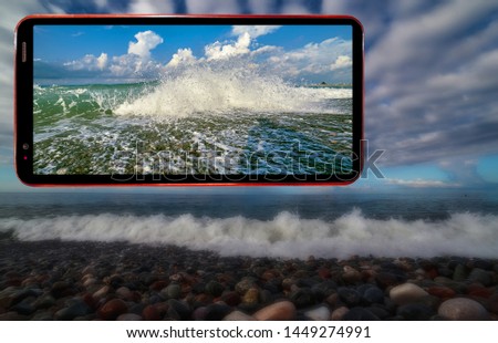 Collage of cell phone screen on darken mystique blurred background of wavy sea beach with wet stones in Sochi region of Black Sea