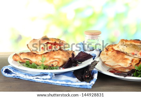 Pizza calzones on plates on nature background