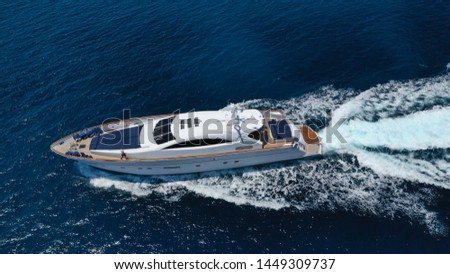 Aerial drone tracking photo of luxury yacht with wooden deck cruising in deep blue waters of Mykonos island, Cyclades, Greece