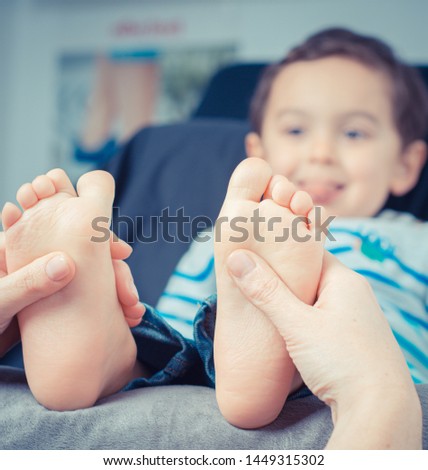 Mother/therapist massaging her child's foot, shallow focus. Close up photo