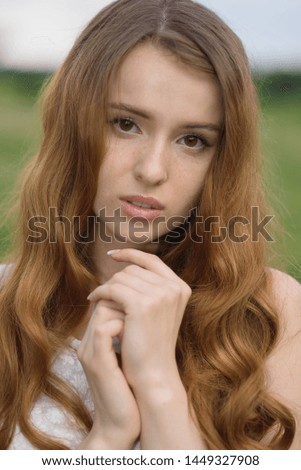 Close-up portrait of an attractive Caucasian redhead young woman on a warm summer day in a park. Beautiful girl with freckles. Natural beauty, fashion, freedom.