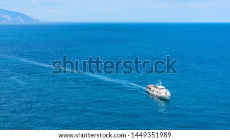 Tourist ship sails in the Black Sea, Crimea, Russia. Aerial marine view. Seascape with lone vessel. Beautiful panorama of the sea and ship. Concept of the sea voyage and travel in summer.