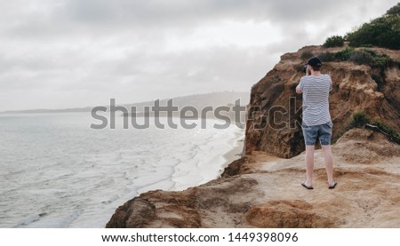 photographer taking photo over cliff and ocean