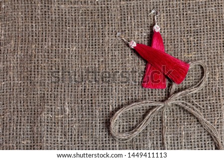 Earrings, tassels lie on a rough linen fabric. Near a bow of linen thread.