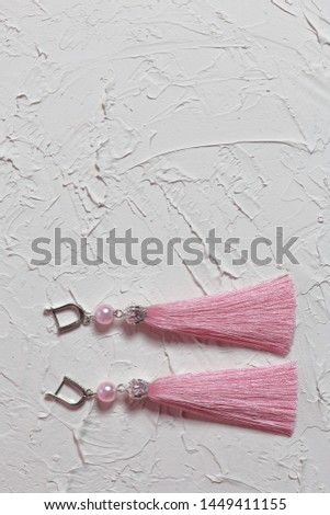 Earrings tassels. They lie on the surface covered with white decorative plaster.