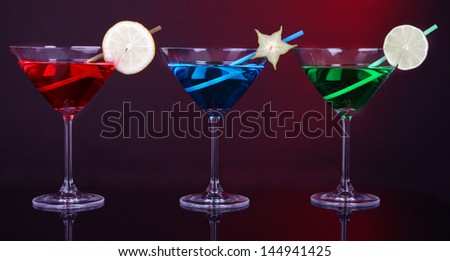 Alcoholic cocktails in martini glasses on dark red background