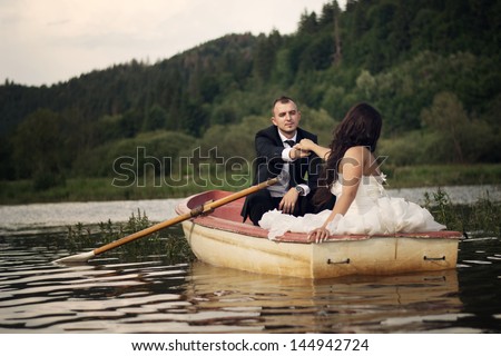 Bride and groom after wedding day, they sit in a boat afloat