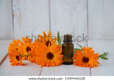 A bottle of calendula tincture, with fresh calendula flowers