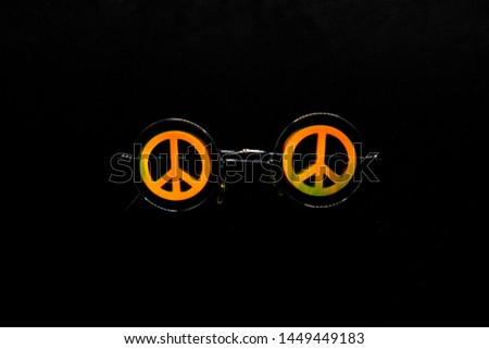 Vintage sunglasses with a symbol of pacifist motion on a black surface.