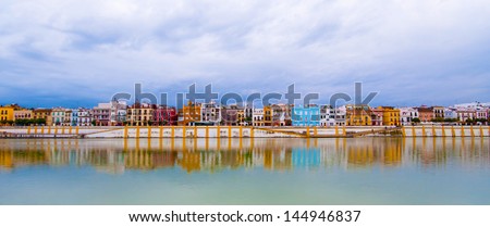 Colorful panorama of Seville riverside on the overcast day, forming amazing pastel colors and reflections in the river.