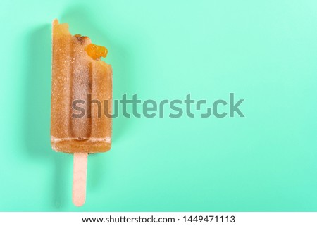 red bean popsicle with couple of bites on light green background