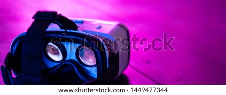 VR 3d 360 headset glasses goggles in futuristic purple neon light on table desk, virtual augmented ar reality innovative experience digital technology background concept, copy space wide photo banner