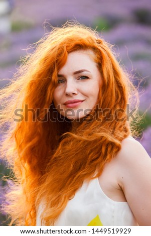Summer portrait of a beautiful girl with long curly red hair. woman with long hair. European girl in lavander field.Golden Fashion Girl Portrait.Wavy Red Hair
