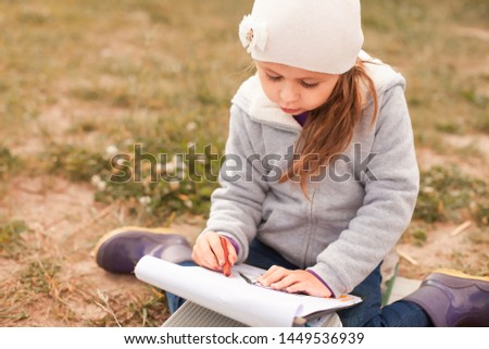 Child girl drawing picture outdoors in summer