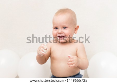 One year baby birthday party. Baby eating birthday cake. The boy on a light background with copy space smash the cake.