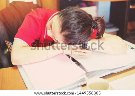 Blurred background of woman sleeps in the office caused from overworking, tired officer is asleep during the office hour, business and education concept picture of a girl studying or doing hard work