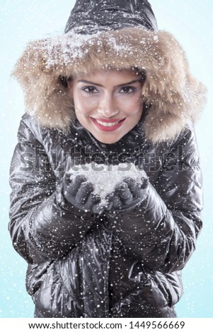 Picture of beautiful woman looks happy while playing with snow in the studio