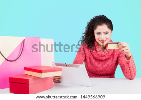 Picture of curly hair woman using a credit card and tablet for shopping online in the studio