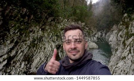 Man making selfie and showing thumb up at Canyon Devil's Gate in Sochi, Russia.