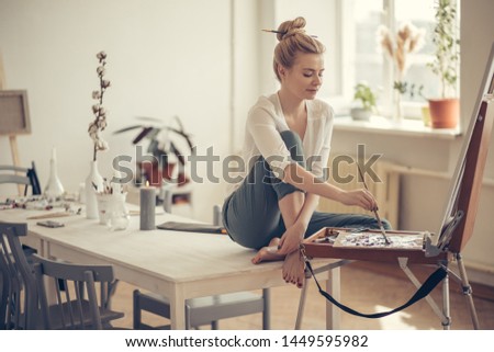 talented artist sitting on the table and drawing her picture at home. full length side view photo. interest, hobby concepts