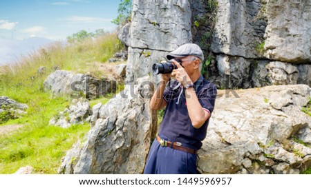 Picture of senior photographer standing near limestones while taking a photo of amazing landscapes