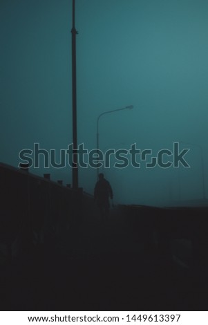 Fisherman goes over the bridge in the fog