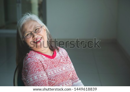 Picture of smiling elderly woman looking at the camera while sitting in a wheelchair