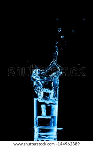 Glass of water with ice cubes on black background