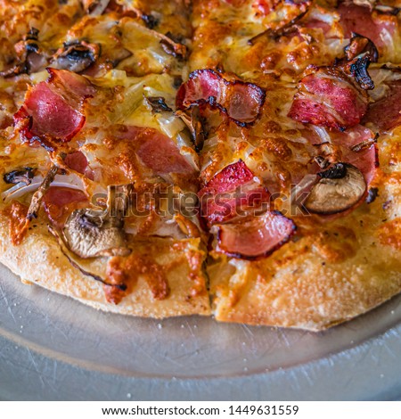Tasty and appetizing Italian pizza with bacon, onion, mushrooms and red chilli