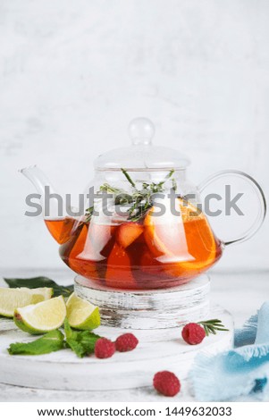 Homemade fruit and berry tea in a glass teapot on a light background