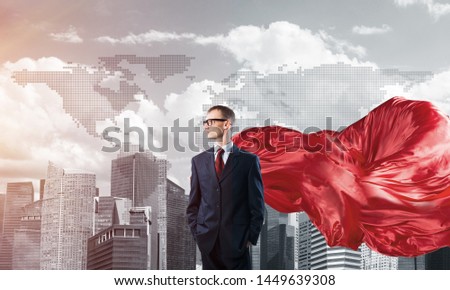 Young confident businessman wearing red cape against modern city background