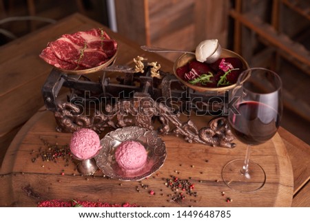 balls of ice cream from beets and meat in an old ice-cream bowl on the background of steaks seasoned beef on a bowl of vintage scales, with mascarpone cheese, beetroot, dried tomato, peppercorns