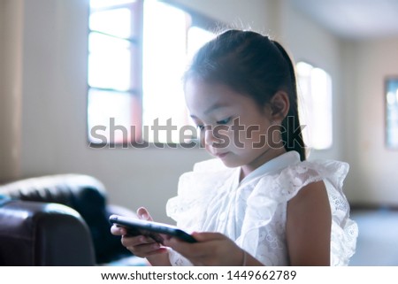 Asian girls playing game online on mobile phones in the living room