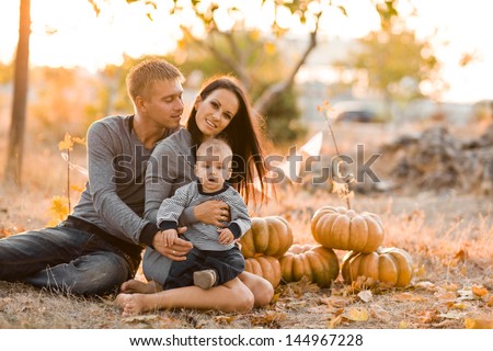 Happy family with pumpkin on autumn leaves. Outdoor.
