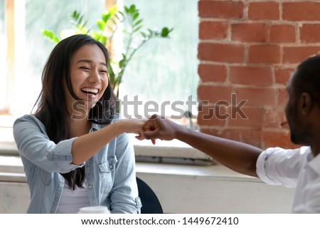 Smiling Asian businesswoman with African American colleague fists bump, employees or students greeting each other, celebrating good teamwork result, having fun together, friendship concept close up Royalty-Free Stock Photo #1449672410
