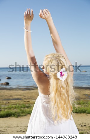 Young woman stretches long hands to blue sky