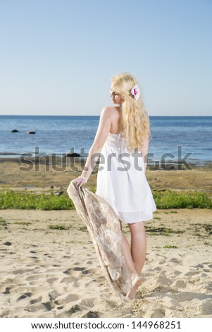 Young woman walking with light scarf at beach
