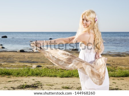 Young woman playing with light scarf at beach