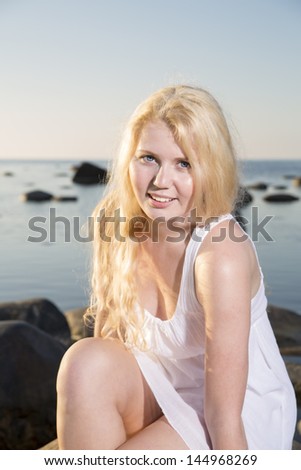Woman in white dress posing on seashore background