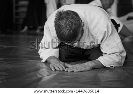 Black and white image of aikido. Athlete in the traditional form of Aikido. White kimano and black hakame. A bow as a sign of respect and welcome. Royalty-Free Stock Photo #1449685814