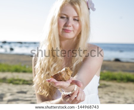 Woman in white dress looking at brown clam