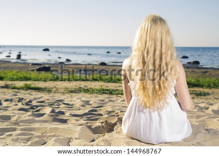 Dreaming woman in white dress on warm beach
