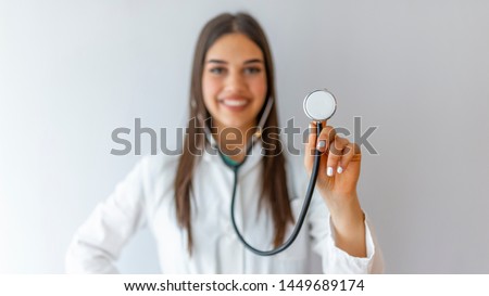 A female doctor holds her stethoscope to insinuate that it's time for a check up in clinic banner panoramic crop for copy space. Smiling medical woman doctor. Isolated over grey background