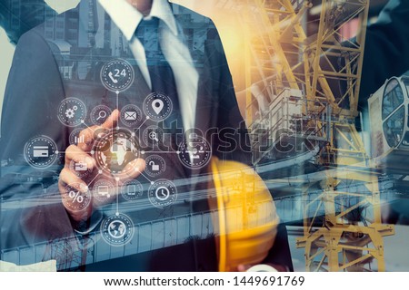 Double exposure engineering using tablet digital technology interfaces icon with construction cranes on city background. Royalty-Free Stock Photo #1449691769
