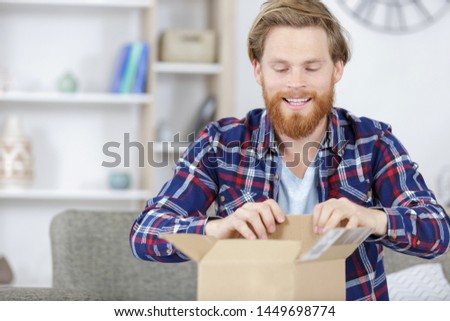smiling and curious man opening his cardbox