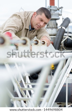 man measuring off metal bar in workshop