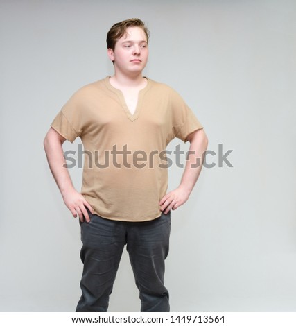 Portrait of a knee on a white background cute young man in a brown T-shirt in jeans. Standing right in front of the camera in various poses, talking, demonstrating emotions.