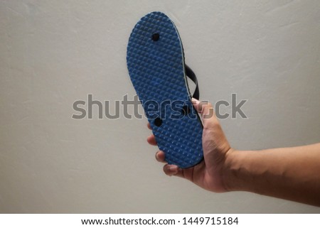 A man holding flip flop or sandal at hand. Royalty-Free Stock Photo #1449715184