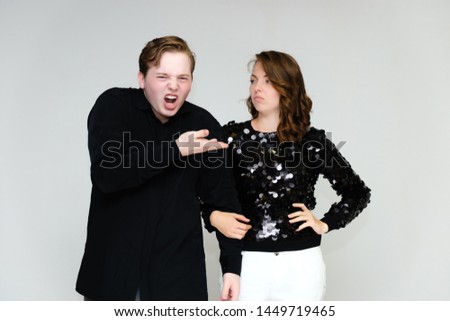 Portrait below the belt on a white background pretty young brunette woman in a black sweater and a young man in a black shirt. Standing in different poses, talking, showing emotions.